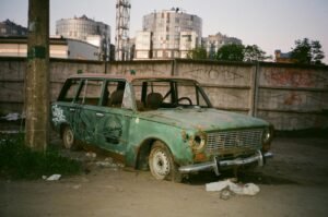 Abandoned vintage car in urban area with graffiti and rust.